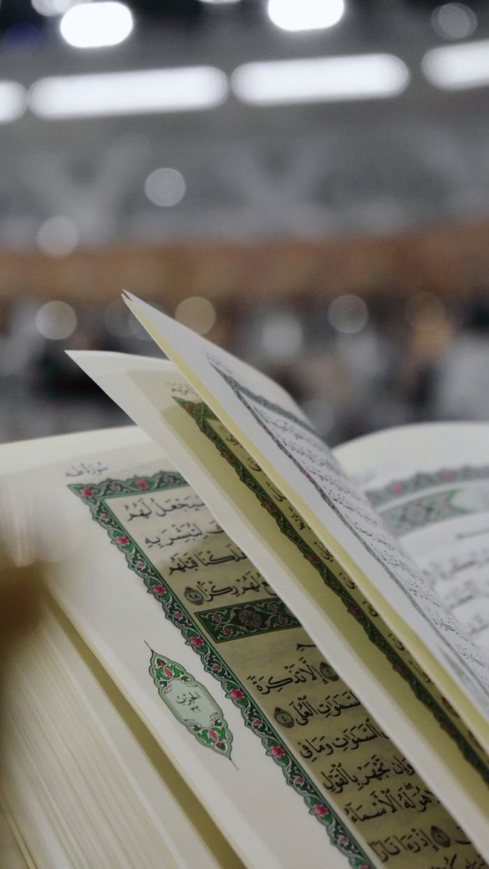 Close-up of an open Quran with Arabic text, blurred background for focus on holy scripture.