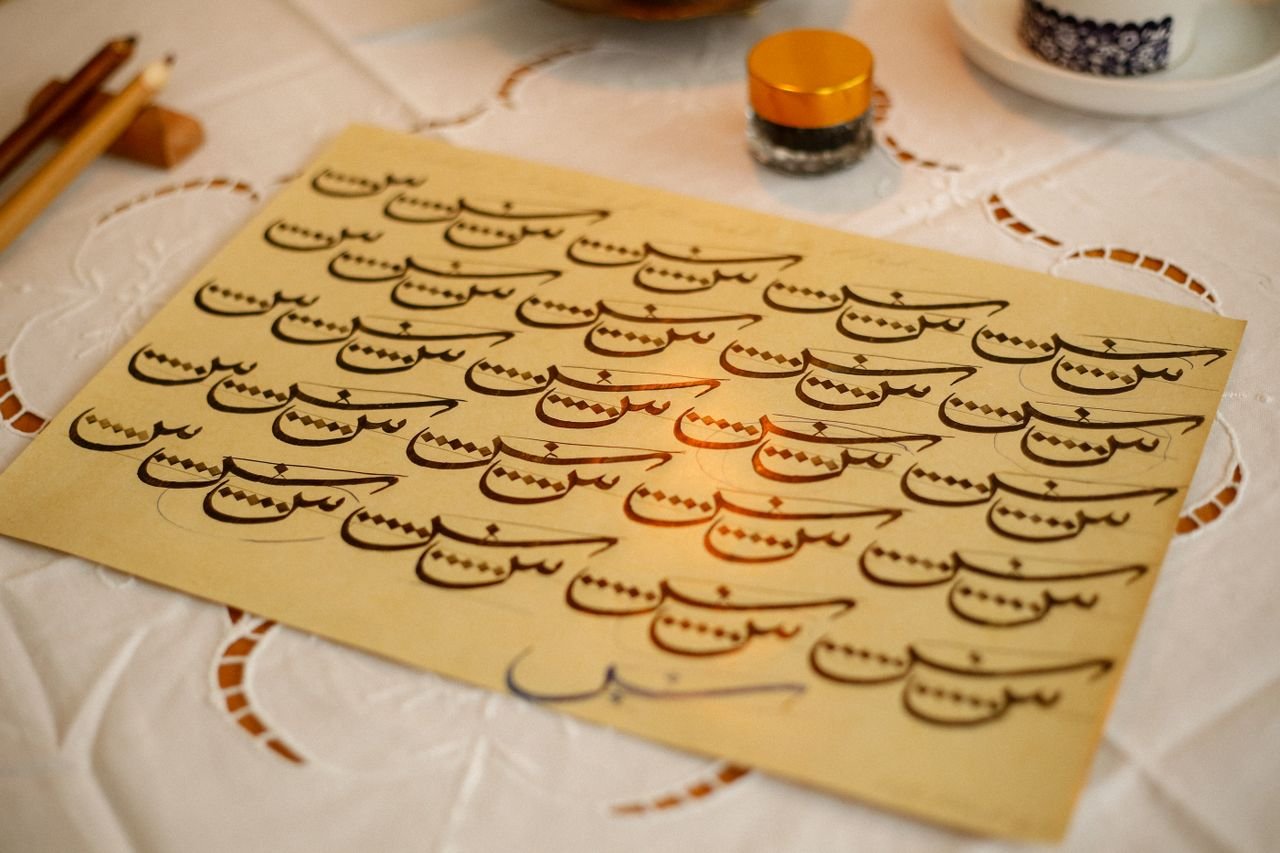 Close-up of artistic Arabic calligraphy on a paper sheet with warm tones.