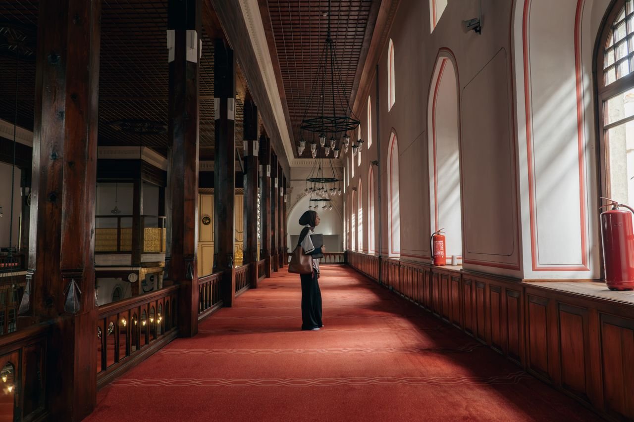 Woman admires the elegant architecture of a mosque interior in Istanbul, Türkiye.